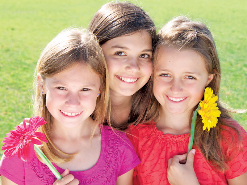 Three girls holding flowers.